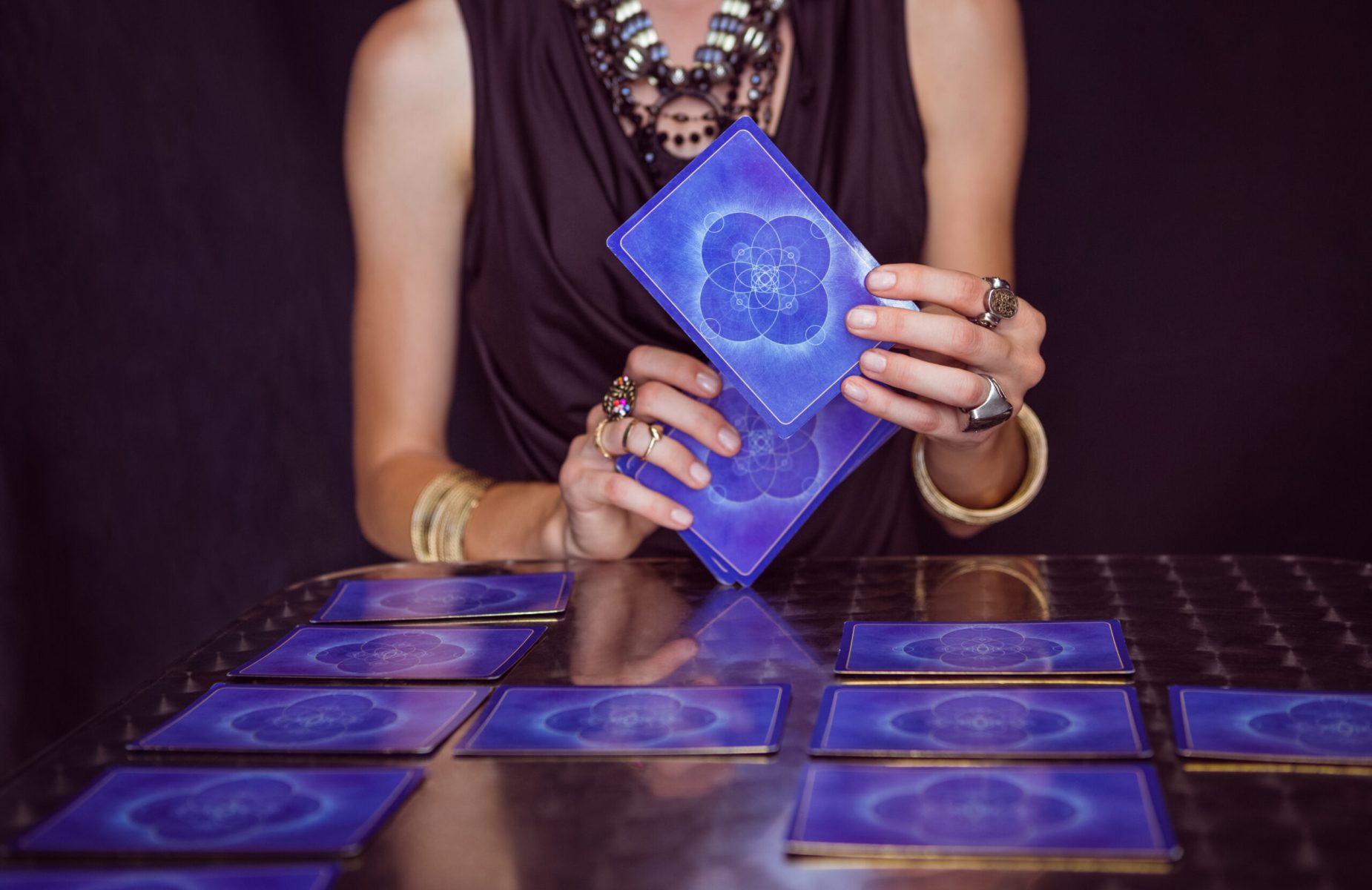 Fortune teller forecasting the future with tarot cards on black background